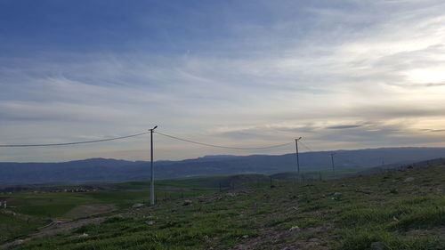 Electricity pylons on landscape against sky