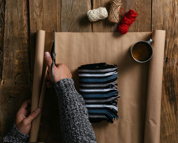 Top view of a man's hands packing a gift on a wooden table