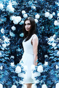 Portrait of beautiful woman standing amidst flowering plants in park