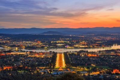 Illuminated cityscape against sky during sunset