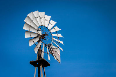 Low angle view of traditional windmill against clear blue sky