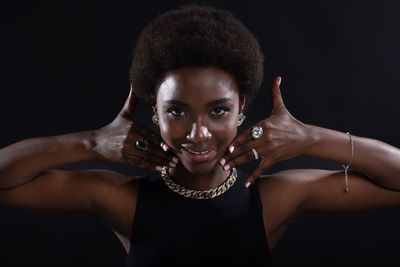 Portrait of young woman standing against black background