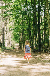 Rear view of woman walking on road in forest