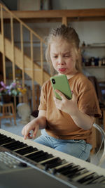 Girl making face while holding phone at home