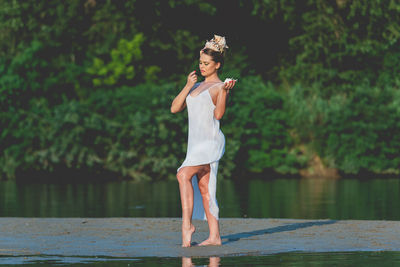 Full length of woman standing by lake