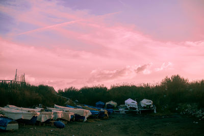 Boats on field against sky during sunset