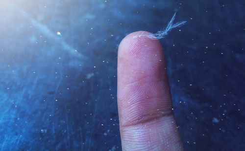 Close-up of hand holding raindrops on leaf