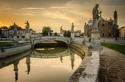 Arch bridge over river at sunset