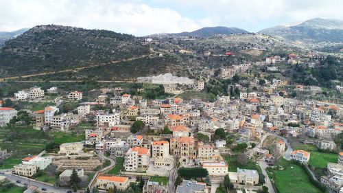 Aerial view of townscape and mountains against sky