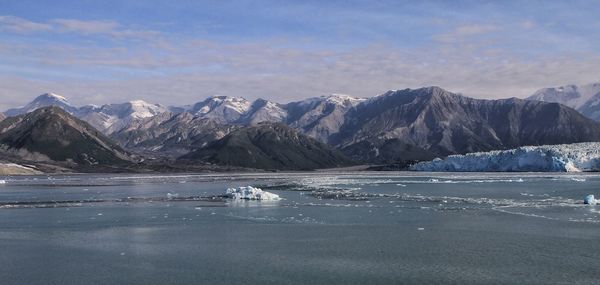 Scenic view of sea by mountains against sky