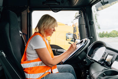 Woman writing while sitting in truck