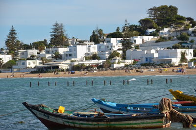 Boats moored in sea by city against sky