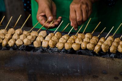 Cropped image of person preparing meat on coals