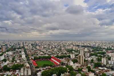 High angle view of city buildings against cloudy sky