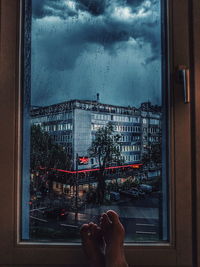 Low section of man by wet window in city during rain