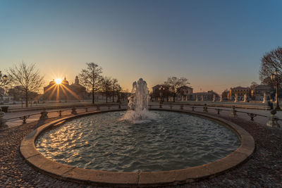 Fountain in swimming pool against sky during sunset