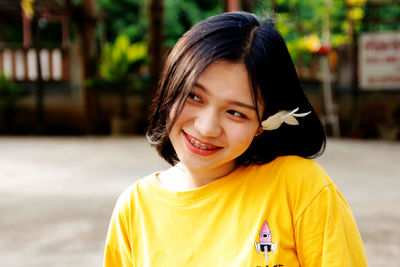 Smiling young woman wearing flower looking away outdoors