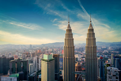 Aerial view of buildings in city against cloudy sky