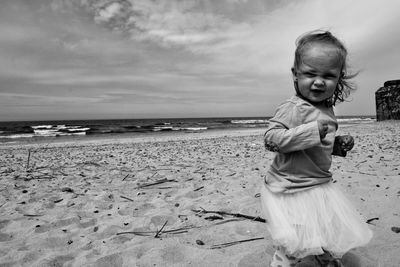 Girl standing at sandy beach against sky