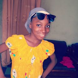 Portrait of smiling young woman standing against wall