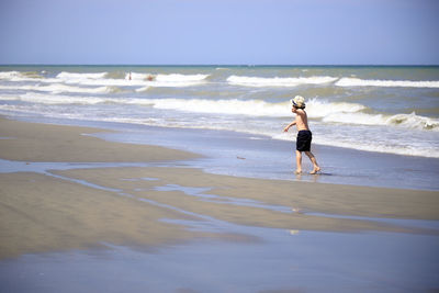 Full length of boy on beach against sky