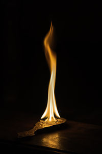 Close-up of burning candle against black background