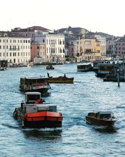 Boats in canal by buildings in city against clear sky