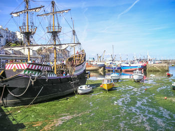 Boats moored at harbor against sky