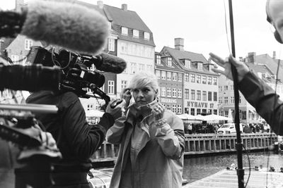 Woman with camera operator standing in city