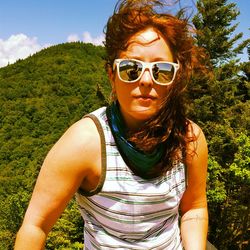 Portrait of mid adult woman wearing sunglasses against mountain in forest