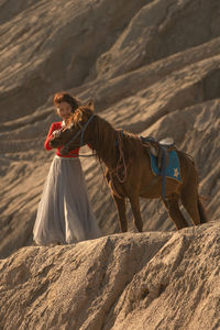 Low angle view of smiling woman with horse standing on mountain