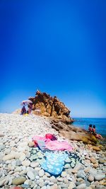 View of rocks on beach against clear blue sky