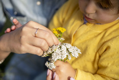 Midsection of woman holding yellow flower