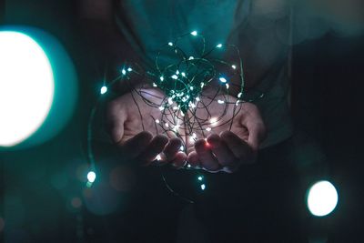 Close-up of hand holding illuminated christmas lights
