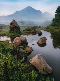 Rocks by lake against sky