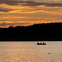 Silhouette people on lake during sunset