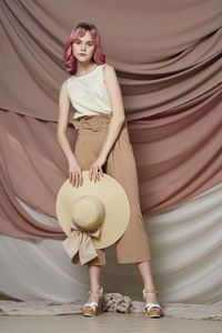 Full length portrait of woman standing against wall