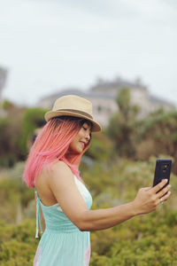 Side view of woman using mobile phone against sky