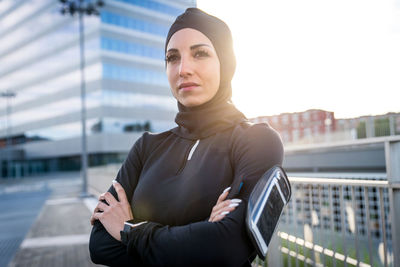 Beautiful woman wearing hijab standing against building during sunrise