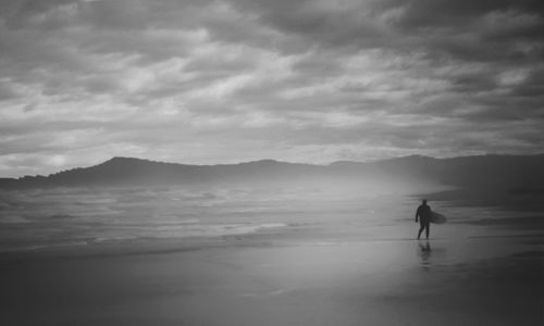 Silhouette man on beach against sky