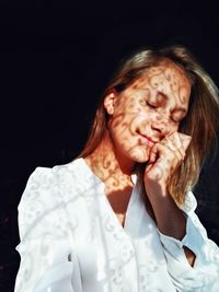 Close-up of woman against black background