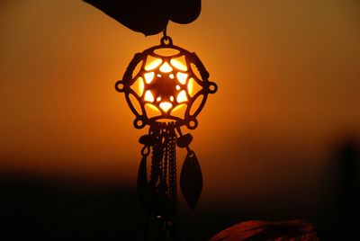 Close-up of illuminated lamp against sky during sunset