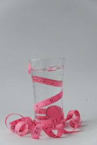 Close-up of pink glass on table against white background