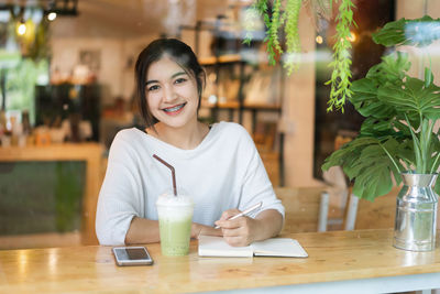 Businesswoman writing on diary while sitting at cafe