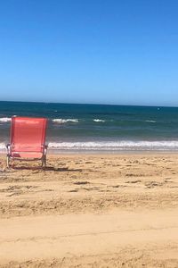 Deck chairs on beach against clear blue sky