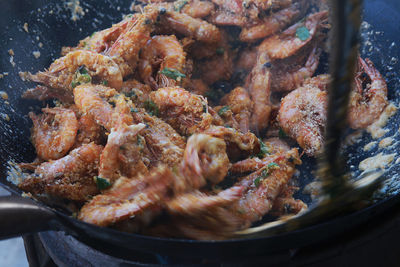 High angle view of ladle stirring shrimps in cooking pan