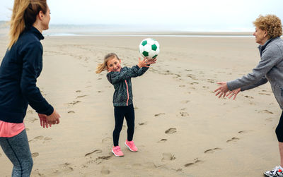 Happy family playing with ball at beach