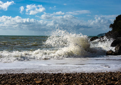 Waves splashing on shore against sky