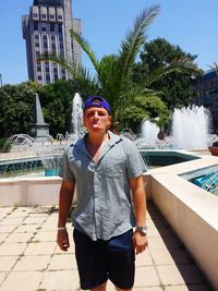 Portrait of young man standing by swimming pool