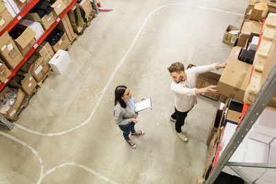 Colleagues discussing while examining cardboard boxes in industry